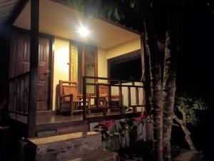 a porch of a house with chairs and a door at Pondok sunset inn in Senaru