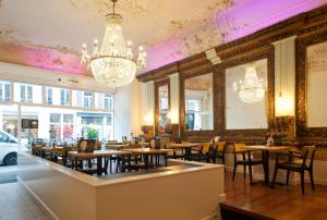a restaurant with wooden tables and chairs and chandeliers at Boutique Hotel De Salon in The Hague