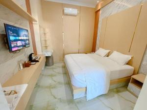 a bedroom with a bed and a television in it at Alzetta Hotel by Abiza in Timuran