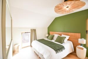 a bedroom with a large bed with a green wall at Le Clos des Cadoles in Les Riceys