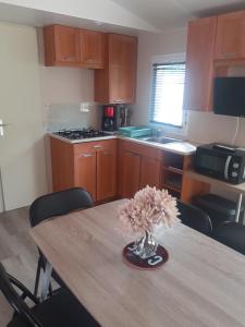 a kitchen with a table with a vase of flowers on it at Le doux refuge de l'Yères in Touffreville-sur-Eu