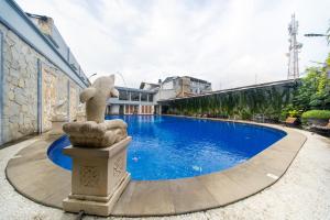 a large swimming pool with a statue next to a building at Horison IJ Kudus in Kudus