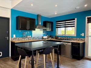 a kitchen with blue walls and a table with chairs at Les TERRASSES DE LAYOULE in Rodez +26 photos