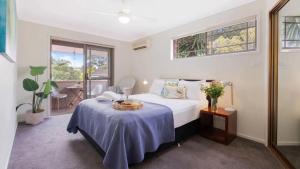 a bedroom with a bed and a table and windows at Bombo Blue in Kiama