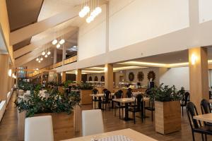 a dining room with tables and chairs and plants at Värska Veekeskuse hotell in Väike-Rõsna