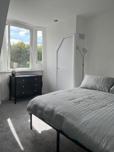 a bedroom with a bed and a dresser and a window at Upper Mill Apartment in Newmilns
