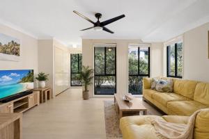 a living room with a couch and a ceiling fan at Hawks Nest Hideaway | Spa, BBQ, Bikes & Pool Table in Hawks Nest