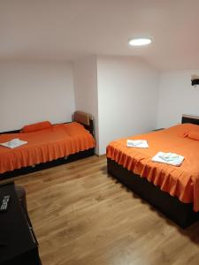 two beds with orange sheets in a room at Casa Crina in Băile Herculane