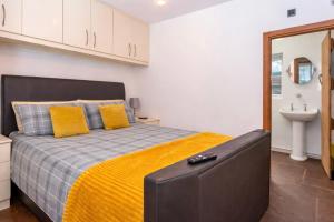 a bedroom with a bed with yellow pillows and a sink at The Shed in Coventry