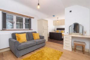 a living room with a gray couch and a tv at The Shed in Coventry +12 photos