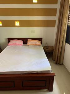 a bedroom with a bed with two pink pillows at AR 7 Villa Mirissa in Matara +2 photos