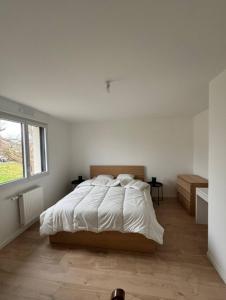 a bedroom with a large bed in a white room at Maison spacieuse - Perros Guirec in Perros-Guirec