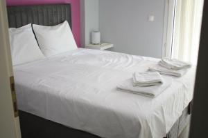 a bed with white sheets and towels on it at Despina's apts in Kalamariá
