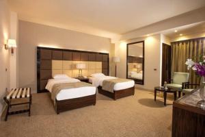 a large hotel room with two beds and a chair at El Mohandseen Cairo Hotel in Cairo