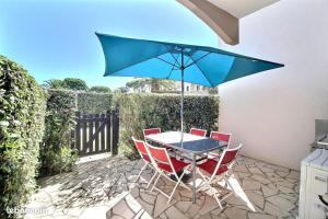 a table and chairs with a blue umbrella on a patio at Le TERMINUS in Saint-Cyprien-Plage