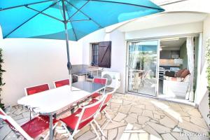 a table and chairs with an umbrella on a patio at Le TERMINUS in Saint-Cyprien-Plage