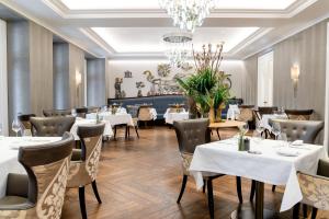 a restaurant with tables and chairs and a chandelier at Royal Savoy Hotel & Spa in Lausanne