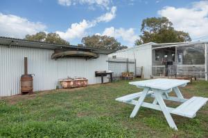a white picnic table in a yard next to a building at Zamenhof River Cabin - Peaceful Farm Escape - Pets Welcome in Yass +17 photos