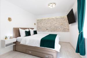 a bedroom with a bed with a green and white comforter at Lions Heritage Rooms in Split
