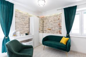 a living room with two green chairs and a stone wall at Lions Heritage Rooms in Split