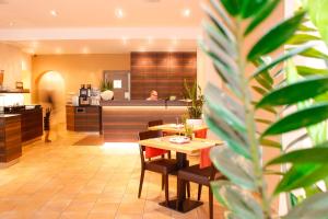a restaurant with a table and chairs and a kitchen at City Hotel Würzburg in Würzburg