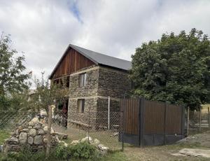 a stone house with a barn with a fence at Sky Tusheti in Omalo