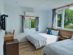 a bedroom with two beds and two windows at 純粹Home 民宿 in Shui-wa-chüeh