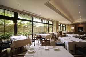 a restaurant with white tables and chairs and windows at Kamakura Park Hotel in Kamakura