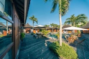 an outdoor deck with tables and chairs and palm trees at Turtle Villas, Canggu by Manara in Canggu