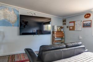 a living room with a leather couch and a map on the wall at Zamenhof River Cabin - Peaceful Farm Escape - Pets Welcome in Yass
