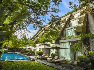 a hotel with a swimming pool and chairs and umbrellas at Maya Sanur Resort & Spa in Sanur