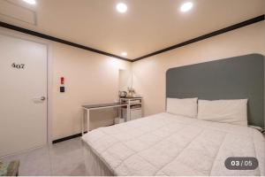 a bedroom with a large white bed with a gray headboard at Prince Motel in Busan +3 photos