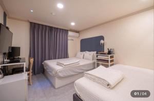 a hotel room with two beds and a television at Prince Motel in Busan