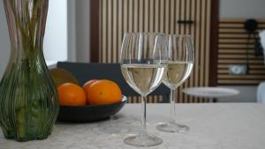 two wine glasses sitting on a table with a bowl of oranges at A Casa Mia 2.0 in Saronno