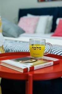 a cup of tea on a red table with a book at דירת סטודיו שקטה עם גקוזי בלב ראשלצ in Rishon LeẔiyyon
