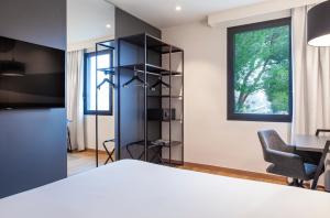 a bedroom with a bed and a chair and a window at SB Madrid Norte in San Sebastián de los Reyes