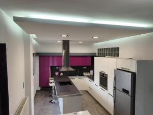 a kitchen with white cabinets and purple walls at DENNIS PATRASSO - Modern apartment in Patras in Patra