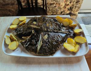 a plate of meat and potatoes on a table at Hostal Viña in Outes