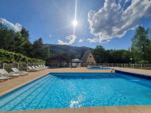 a swimming pool with chairs and a house at Villages de Chalets et camping La Pierre de l'Aigle in La Bréole
