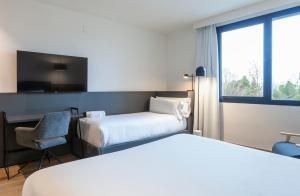 a hotel room with two beds and a desk and a chair at SB Madrid Norte in San Sebastián de los Reyes +11 photos