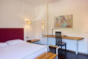 a bedroom with a bed and a desk and a chair at Baveno Beach - Charming Flat With Garden in Baveno