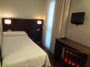 Dormitorio pequeño con cama y TV en Hotel Irixo en Ourense