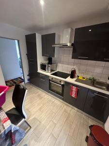 a kitchen with black cabinets and a counter top at Appartement proche aéroport in Blotzheim