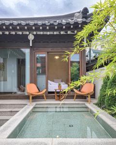 a house with a swimming pool and two chairs at 안동 108한옥 in Andong