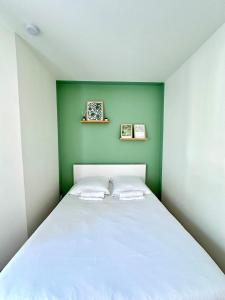 a bedroom with a white bed with a green wall at Le Nid du Petit-Quevilly in Le Petit-Quevilly