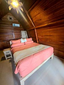 a large bed in a room with a wooden wall at Sandy Beach Villas in Toyapakeh +11 photos