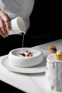 a person is pouring food onto a plate on a table at H15 Palace, a Luxury Collection Hotel, Krakow in Krakow