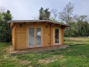 a small wooden cabin with a porch in a field at Chambre d'hôte le petit chalet in Sénas