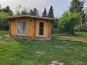a small wooden cabin in a grass field at Chambre d'hôte le petit chalet in Sénas +7 photos