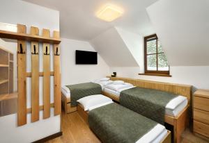 a room with four beds and a tv at Majláthova Chata Popradské Pleso in Vysoké Tatry